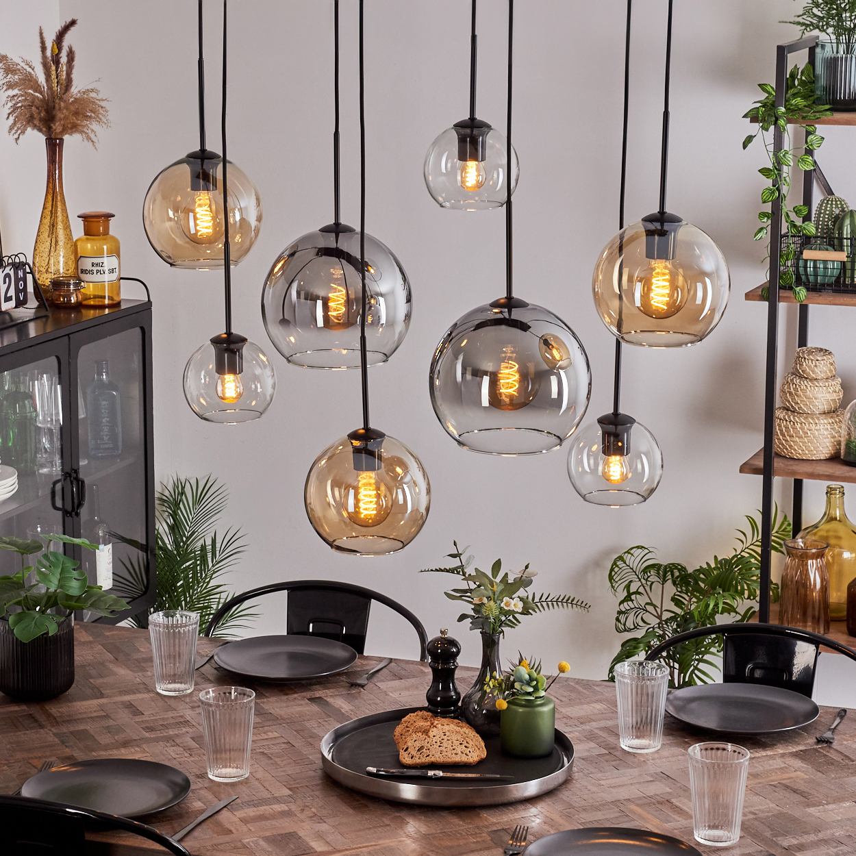 Esszimmer mit Hängelampen, Esstisch und Dekorationen. Lampen haben Glaskugeln.