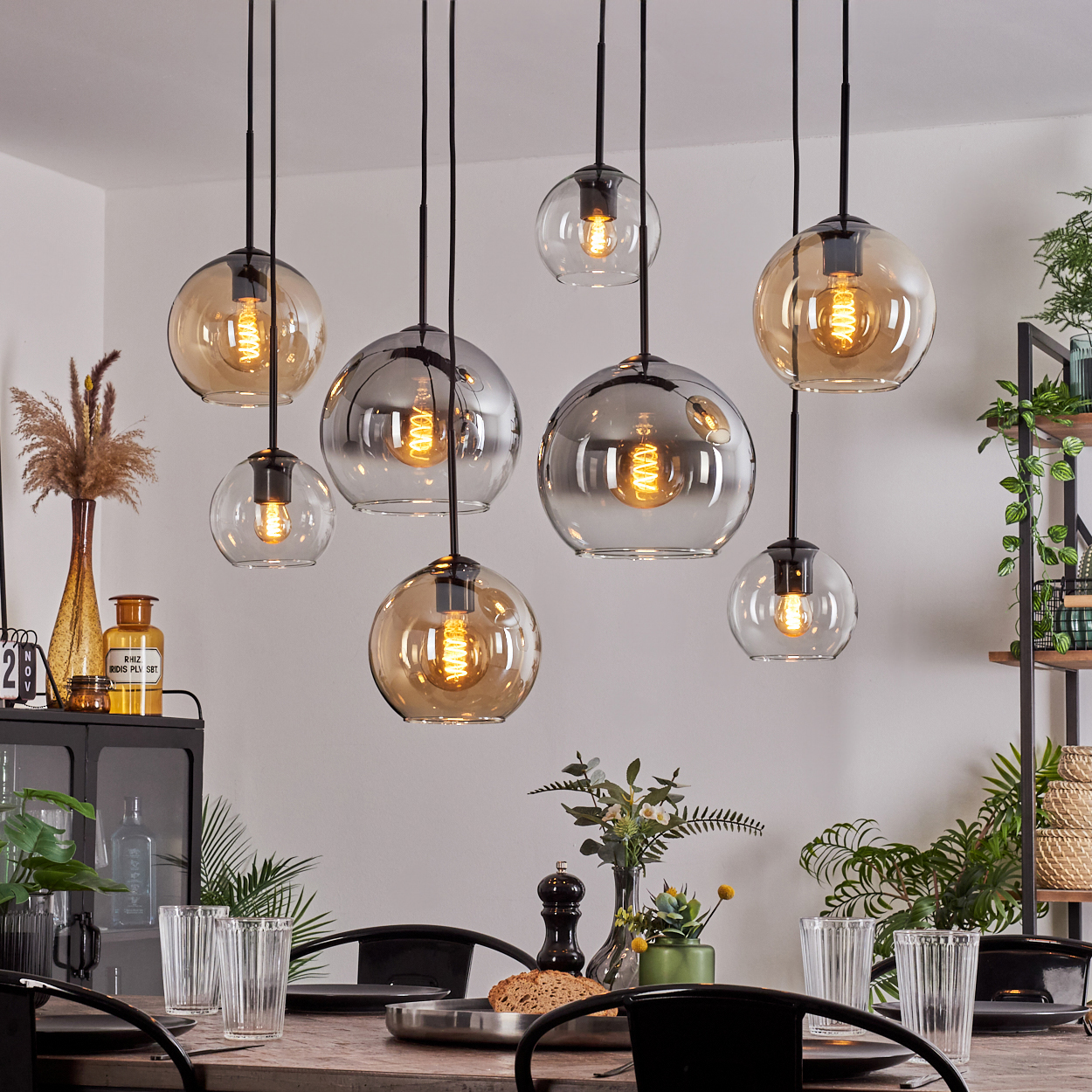 Esszimmer mit mehreren Hängelampen, Tisch und Dekorationen. Lampen haben Glaskugeln.