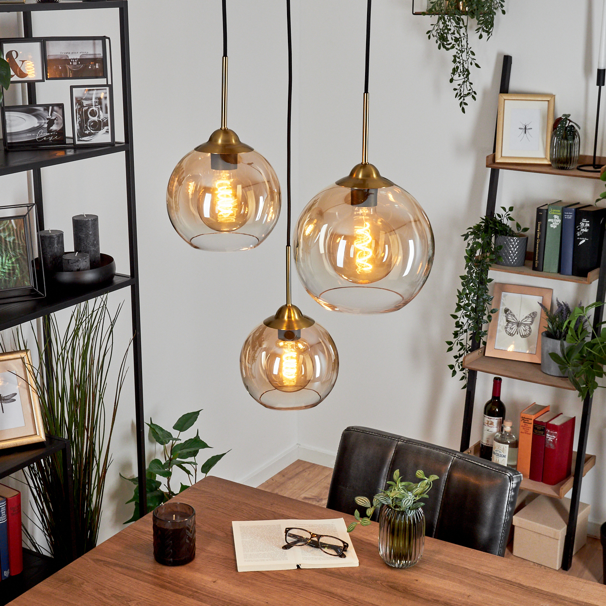 Esszimmer mit drei Pendelleuchten. Bernsteinfarbene Glasschirme, Edison-Glühbirnen und ein Holztisch.