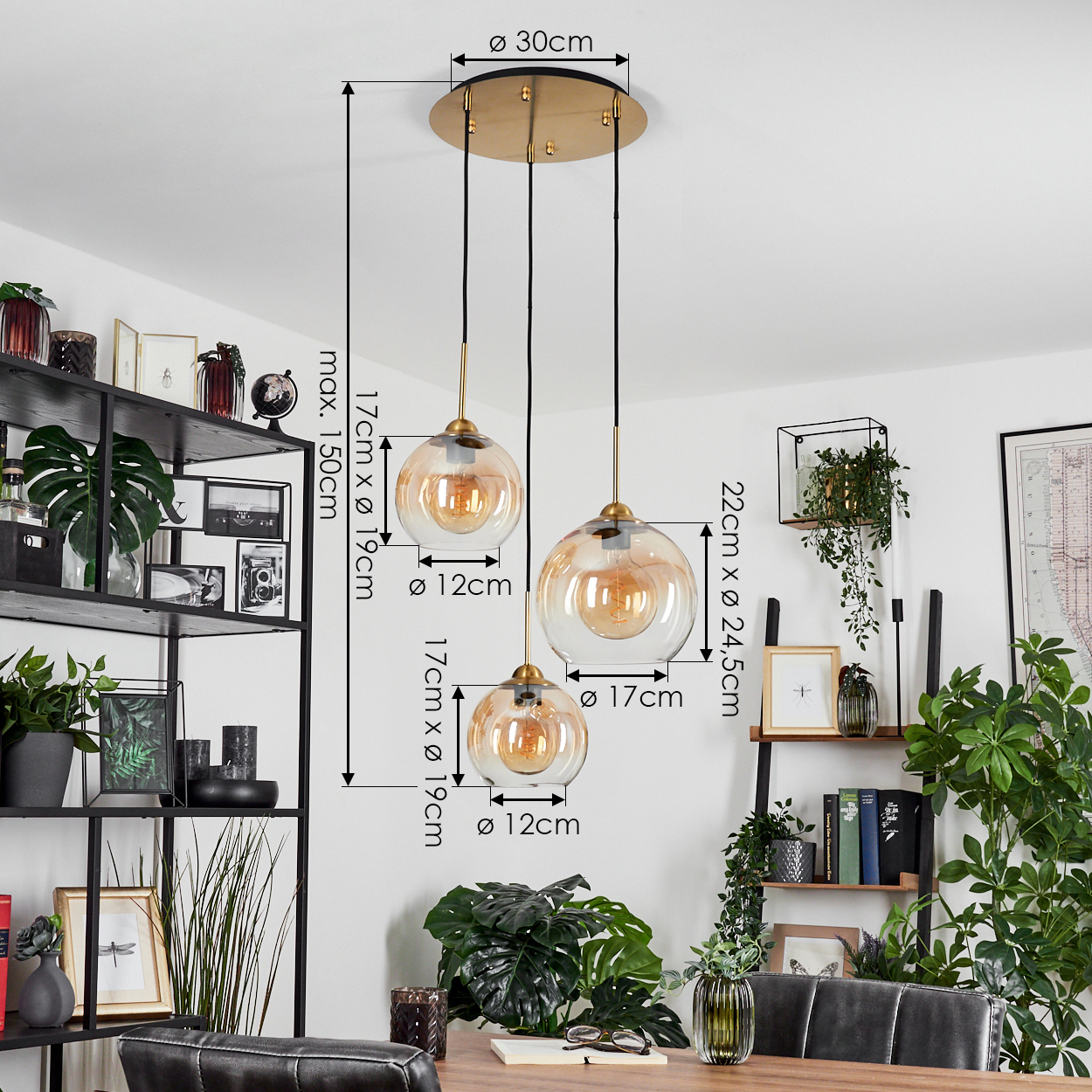 Drei hängende Pendelleuchten. Kugeln mit bernsteinfarbenem Licht. Abmessungen angegeben. Schwarze Regale mit Objekten.