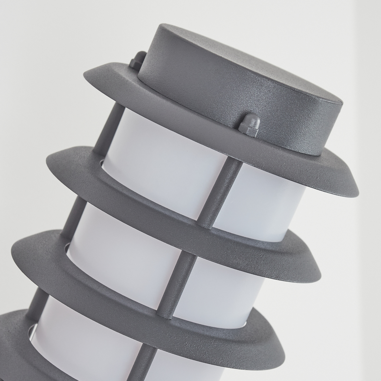 Graue Außenlampe mit zylindrischem Design und weißem Innenlicht.