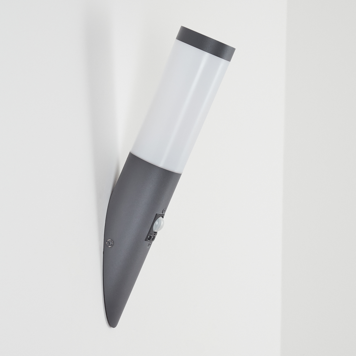 Graue Außenlampe an einer weißen Wand, die die Seite mit dem Sensor zeigt.