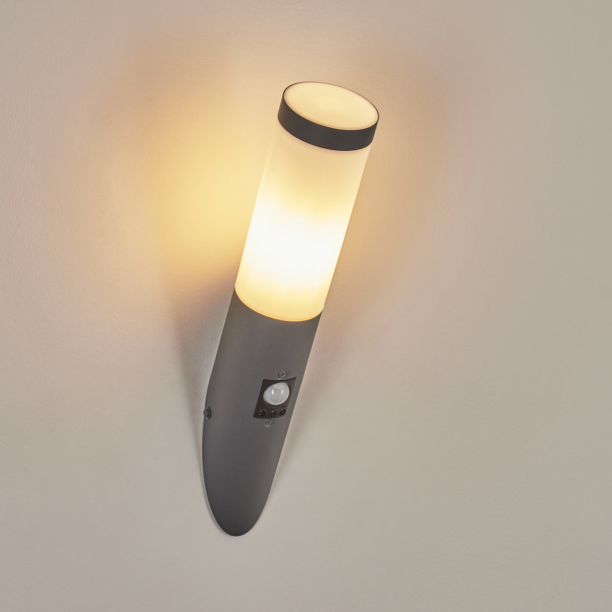 Graue Wandleuchte. Weißer Lichtabschnitt und Sensor. Licht ist an.