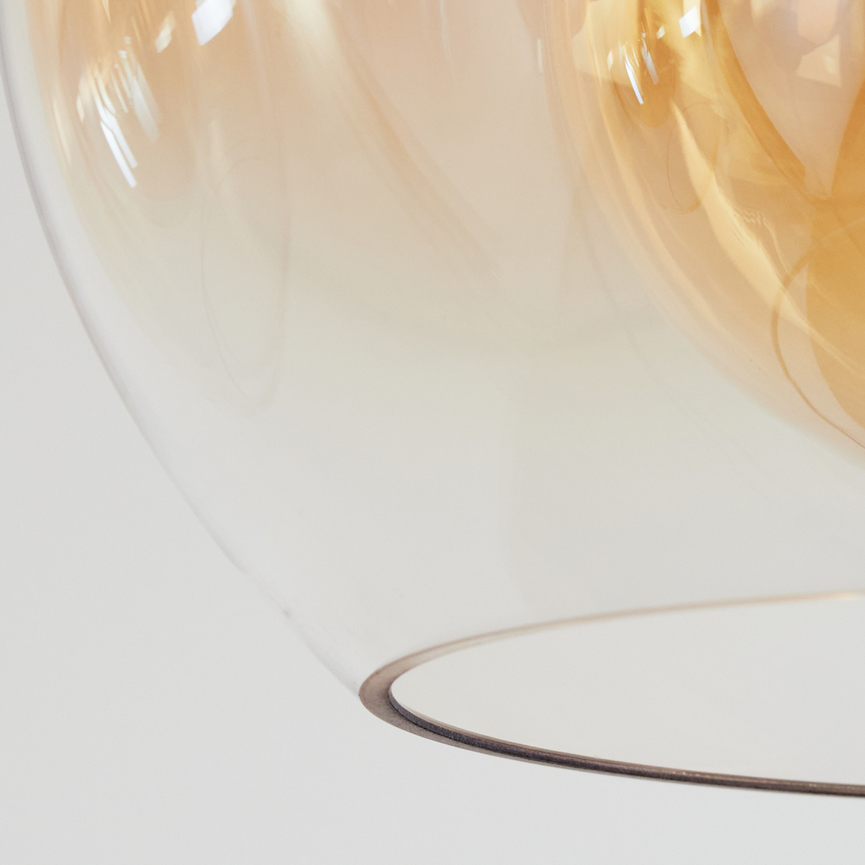 Nahaufnahme einer Glaskugel-Pendelleuchte, die Glas und Metallrand zeigt.