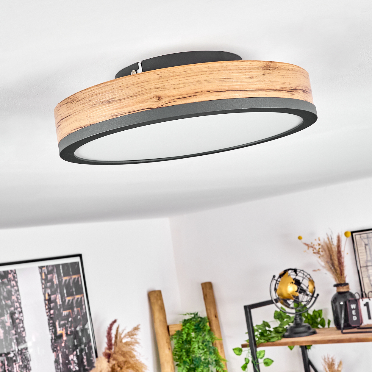 Deckenleuchte mit Holzrahmen, schwarzem Rand und weißem Lichtpaneel. Wohndeko im Hintergrund.