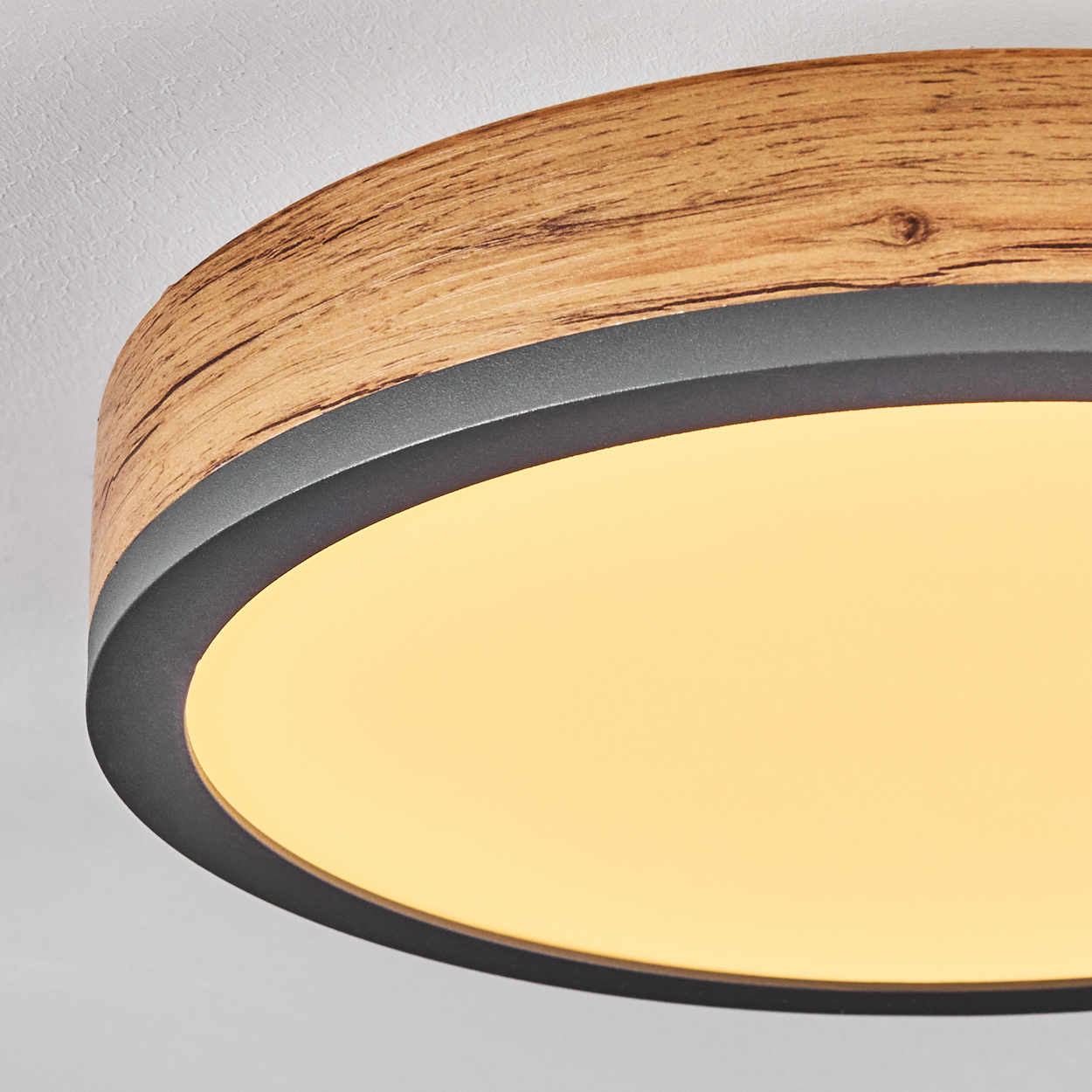 Nahaufnahme einer Deckenleuchte. Holzrahmen mit schwarzem Rand und hellem weißen Lichtpaneel.
