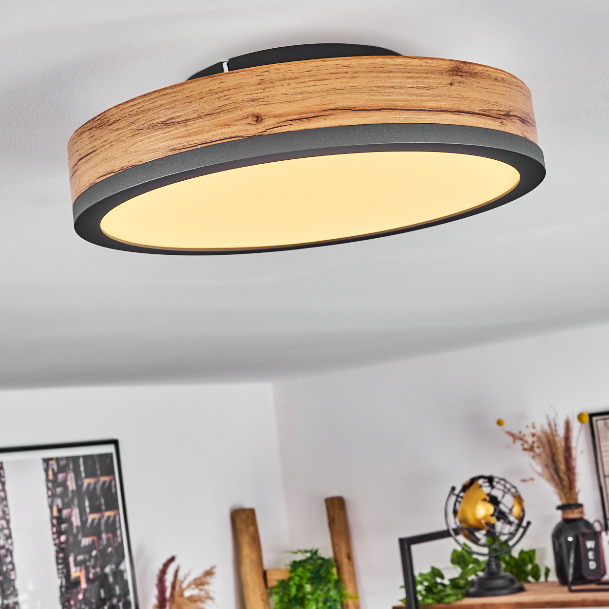 Ovale Deckenleuchte aus Holz mit schwarzem Rand und Licht. Der Hintergrund ist ein Rauminnenraum.