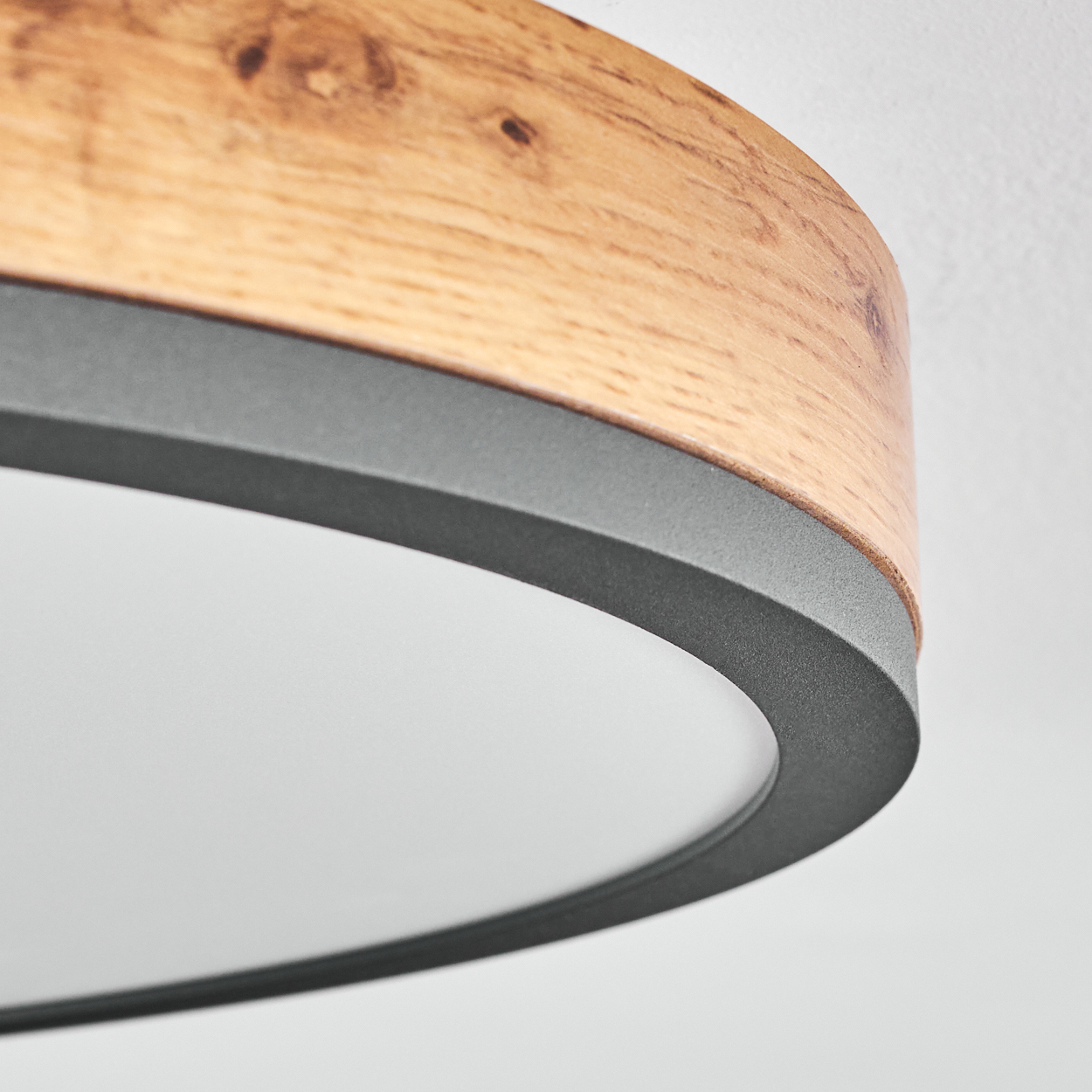 Nahaufnahme einer Deckenleuchte mit Holzrahmen und weißem, rundem Lichtpaneel.