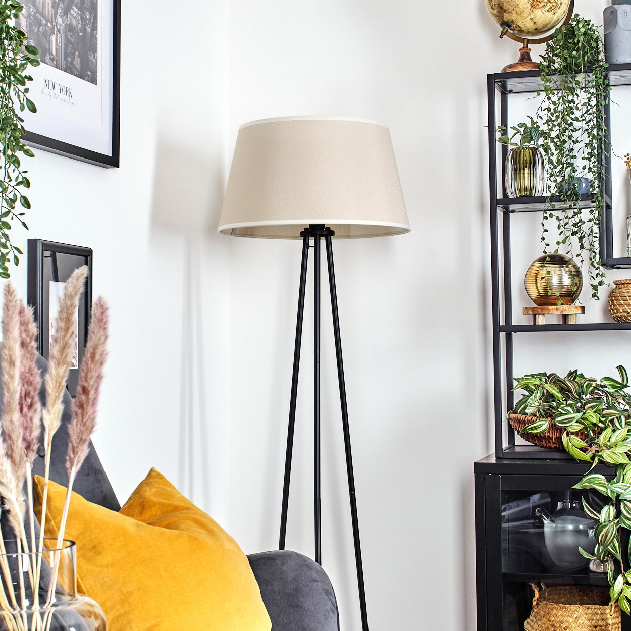Eine Stehlampe mit beigem Schirm und schwarzem Rahmen befindet sich im Raum.