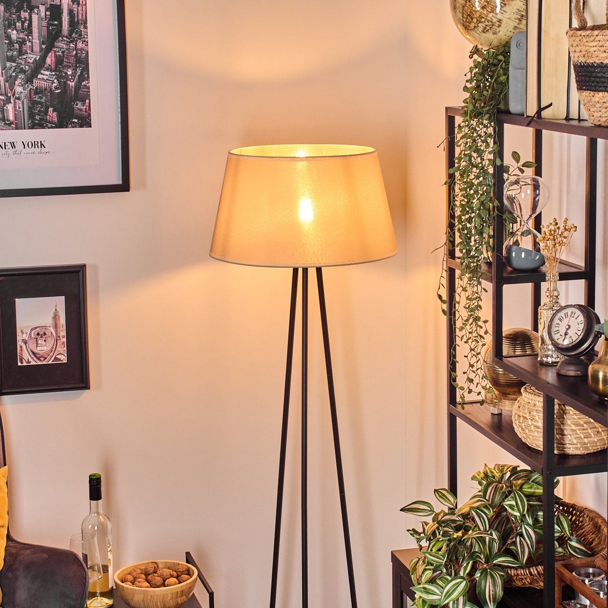 Stehlampe mit beigem Schirm in einem Wohnzimmer mit Dekoration.