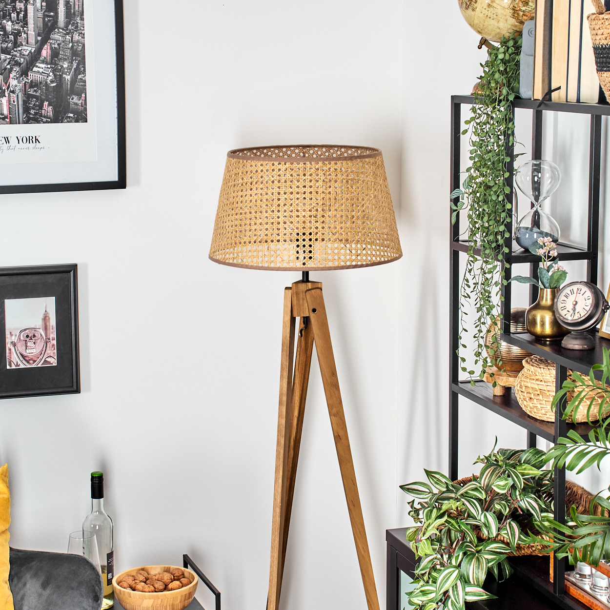 Eine Lampe mit einem gewebten Lampenschirm auf einem hölzernen Stativ, in einem Raum mit Dekorationen.