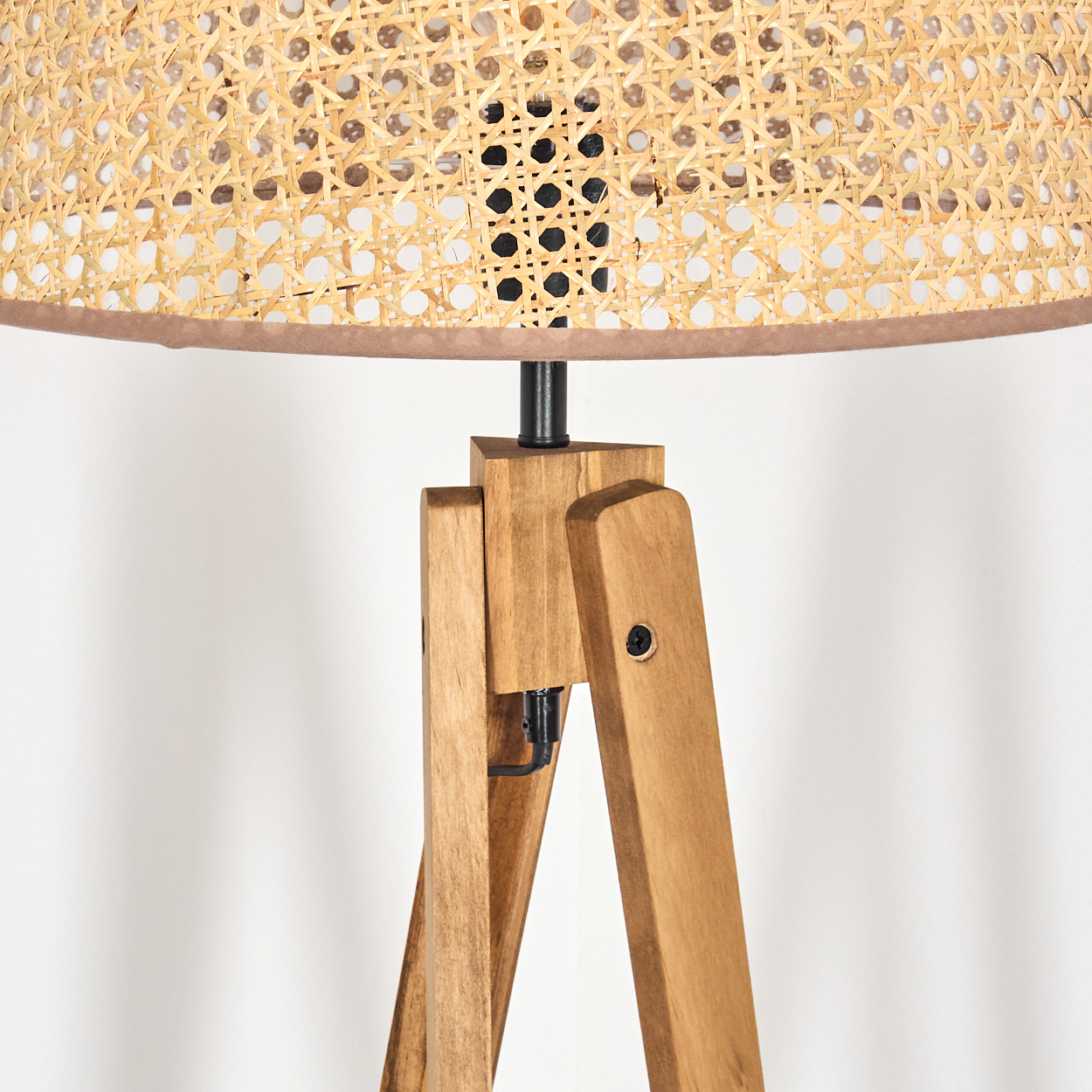 Nahaufnahme des Holzstativs einer Lampe mit gewebtem Lampenschirm. Lampenfuß und Holzdetails sichtbar.