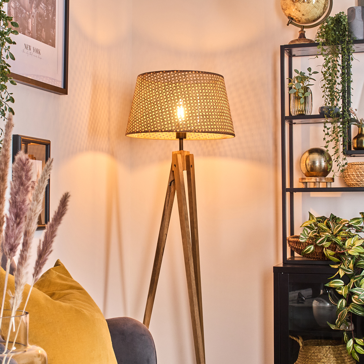Innenaufnahme mit einer Holzlampe, einem gelben Kissen und einem schwarzen Regal, beleuchtet.