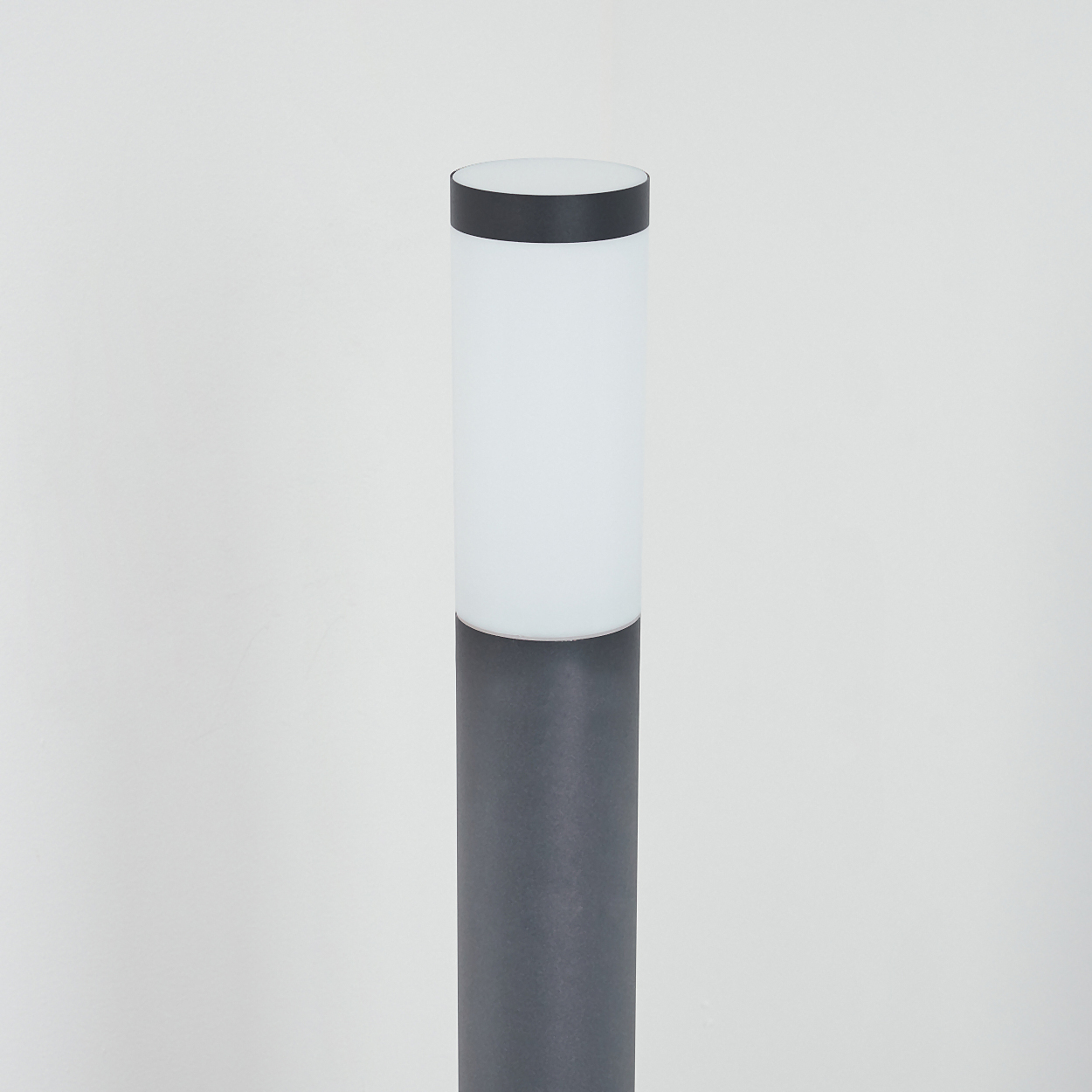 Nahaufnahme einer grauen zylindrischen Lampe mit weißem Oberteil. Auf weißem Hintergrund.