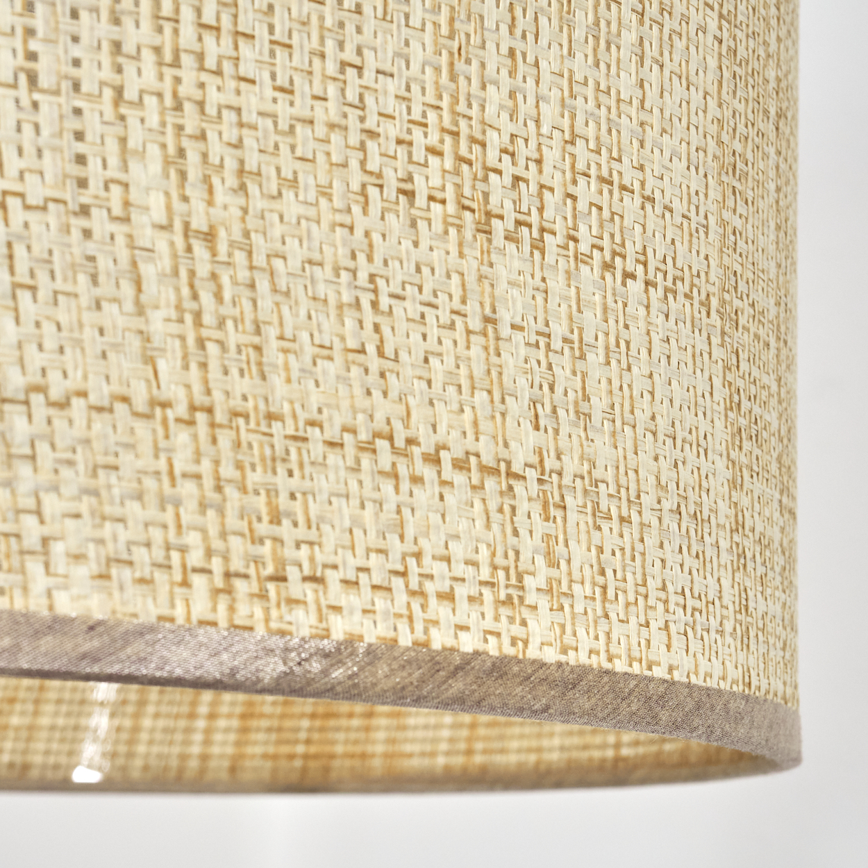 Nahaufnahme des beigen Stoffschirms einer Lampe, die die gewebte Textur zeigt.