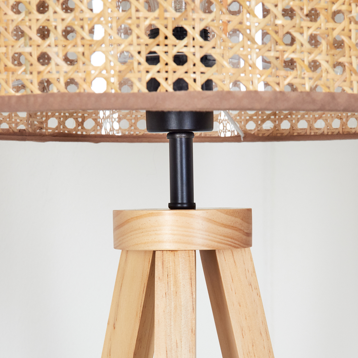 Ein Lampensockel aus Holz mit einem gewebten Lampenschirm, auf weißem Hintergrund.