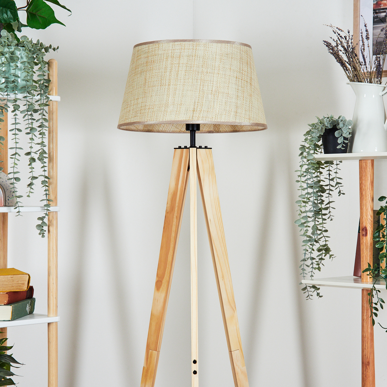 Eine hölzerne Stativ-Stehlampe mit beigem Leinen-Lampenschirm, in einer Raumsituation.