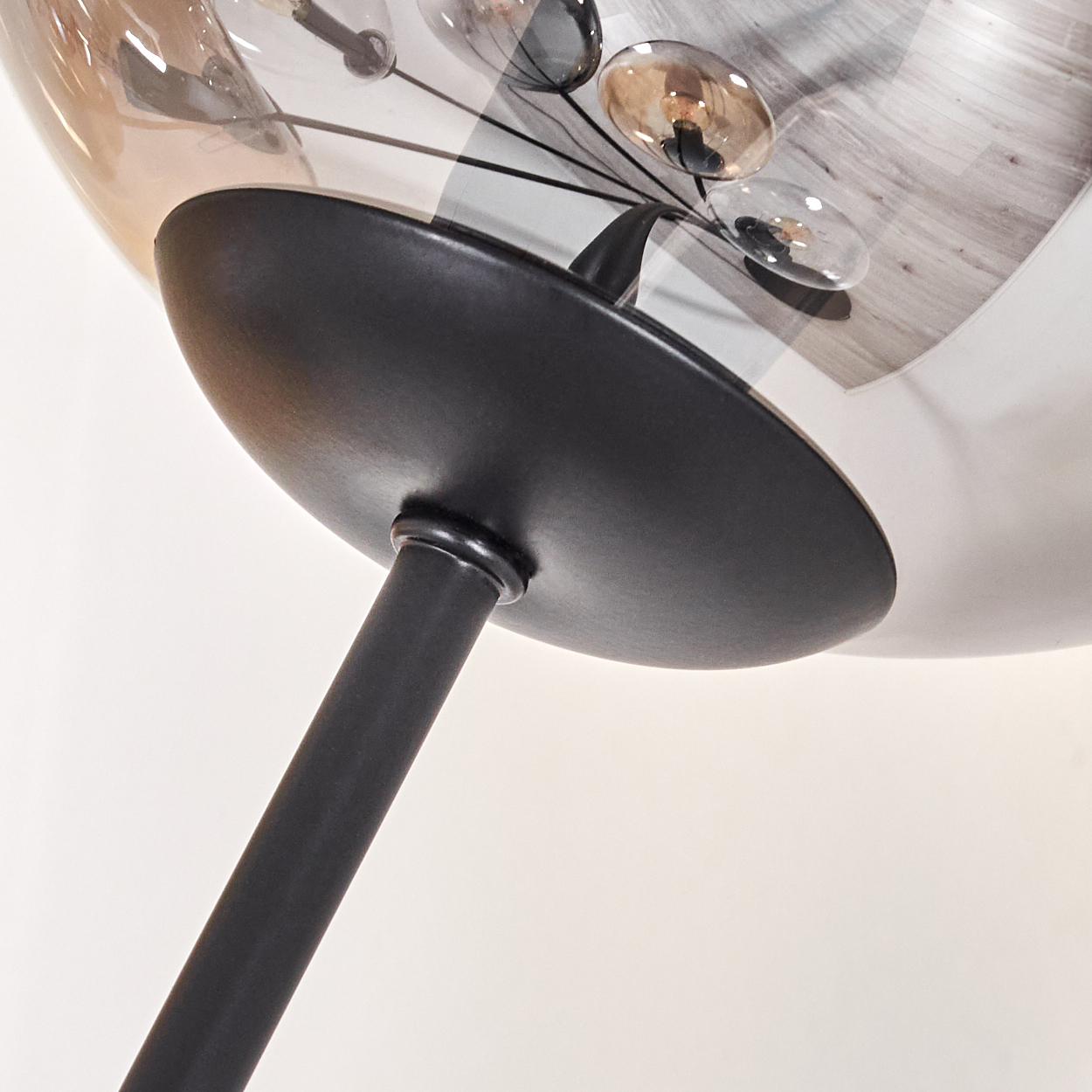 Nahaufnahme einer modernen Lampe mit Glaskugeln. Schwarzer Sockel und Tragstruktur.