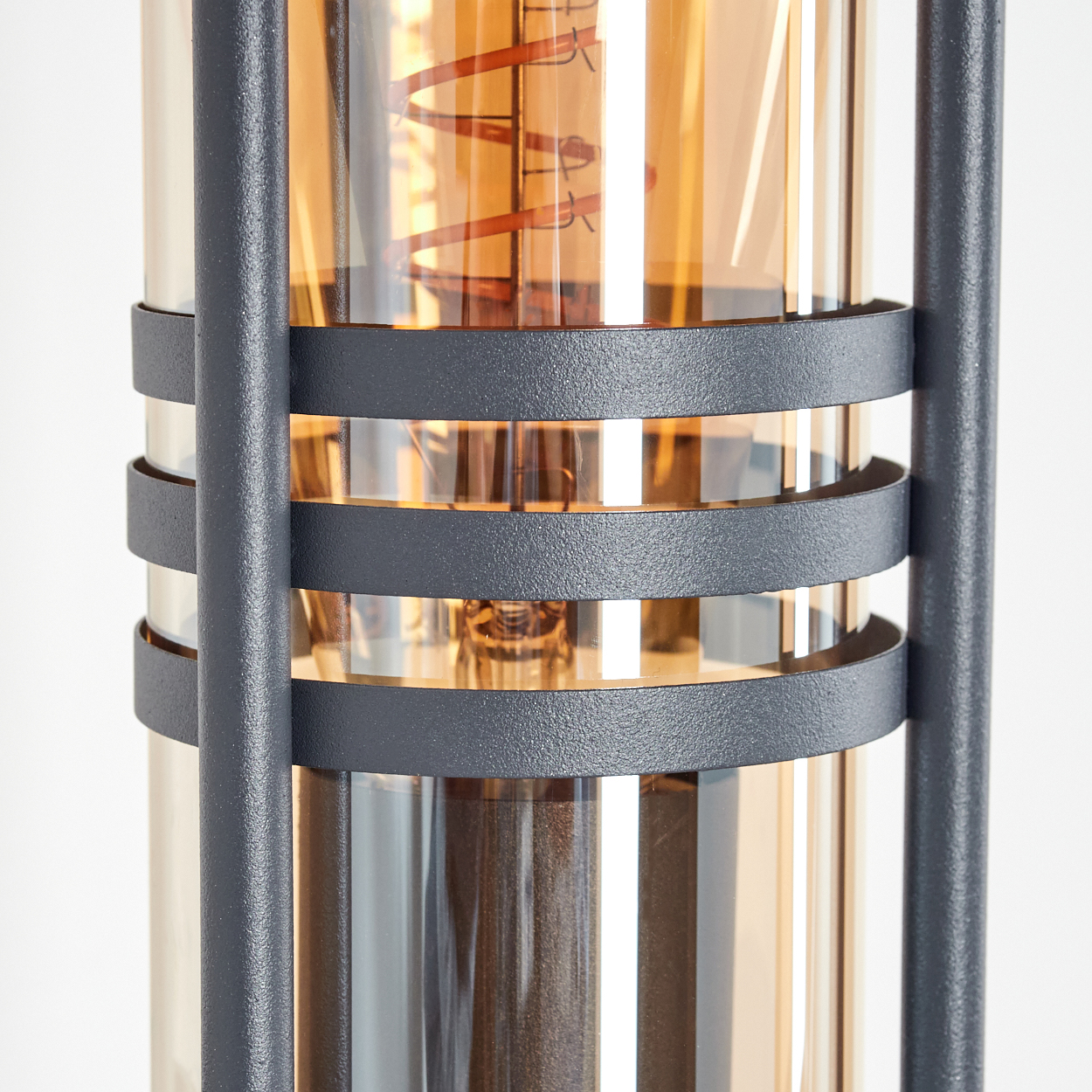 Nahaufnahme einer Außenlampe. Sie hat ein zylindrisches Design mit warmem Licht.