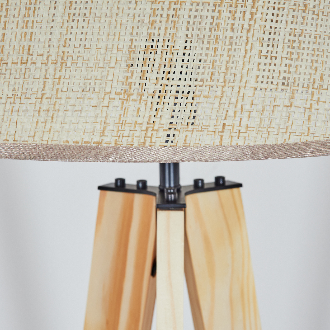 Nahaufnahme einer hölzernen Stativ-Stehlampe. Der Lampenschirm ist aus beigem Stoff.