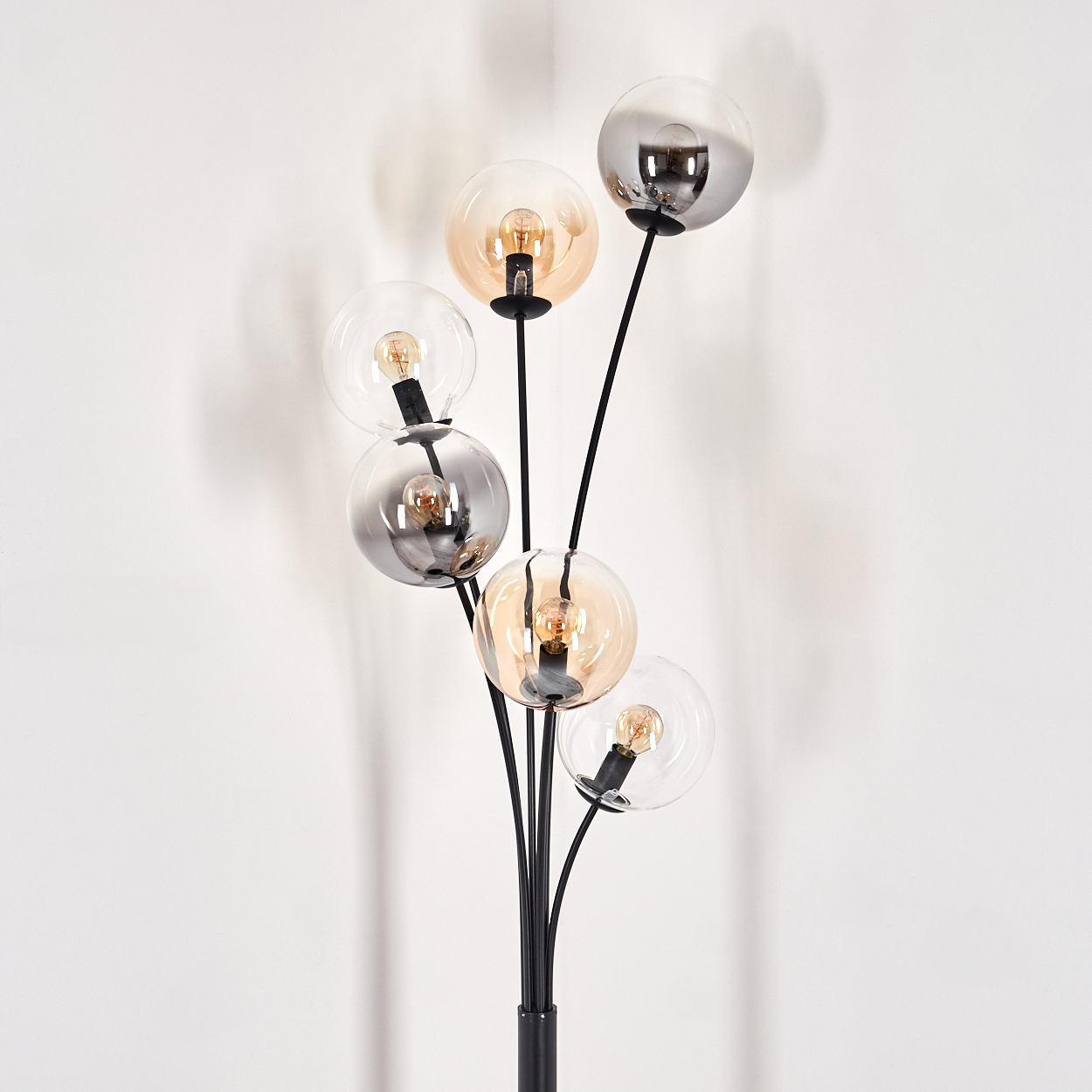 Eine schwarze Stehlampe mit sechs Glaskugeln in verschiedenen Farbtönen auf weißem Hintergrund.