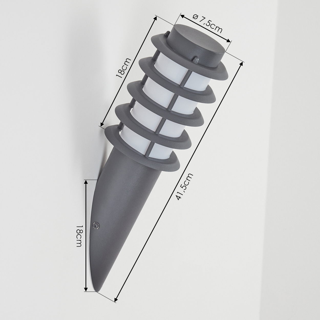 Eine graue Außenlampe mit Maßen. Sie ist an einer weißen Wand montiert.