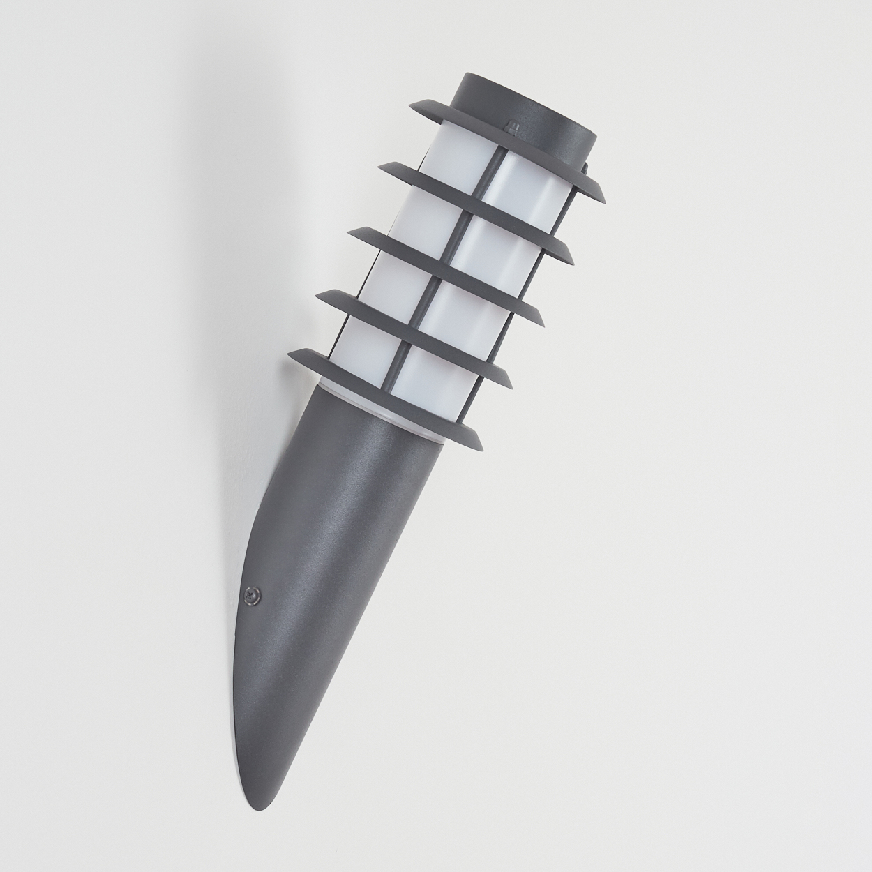 Graue Außenlampe an einer weißen Wand montiert. Die Lampe hat ein einzigartiges Design mit gebogener Form.