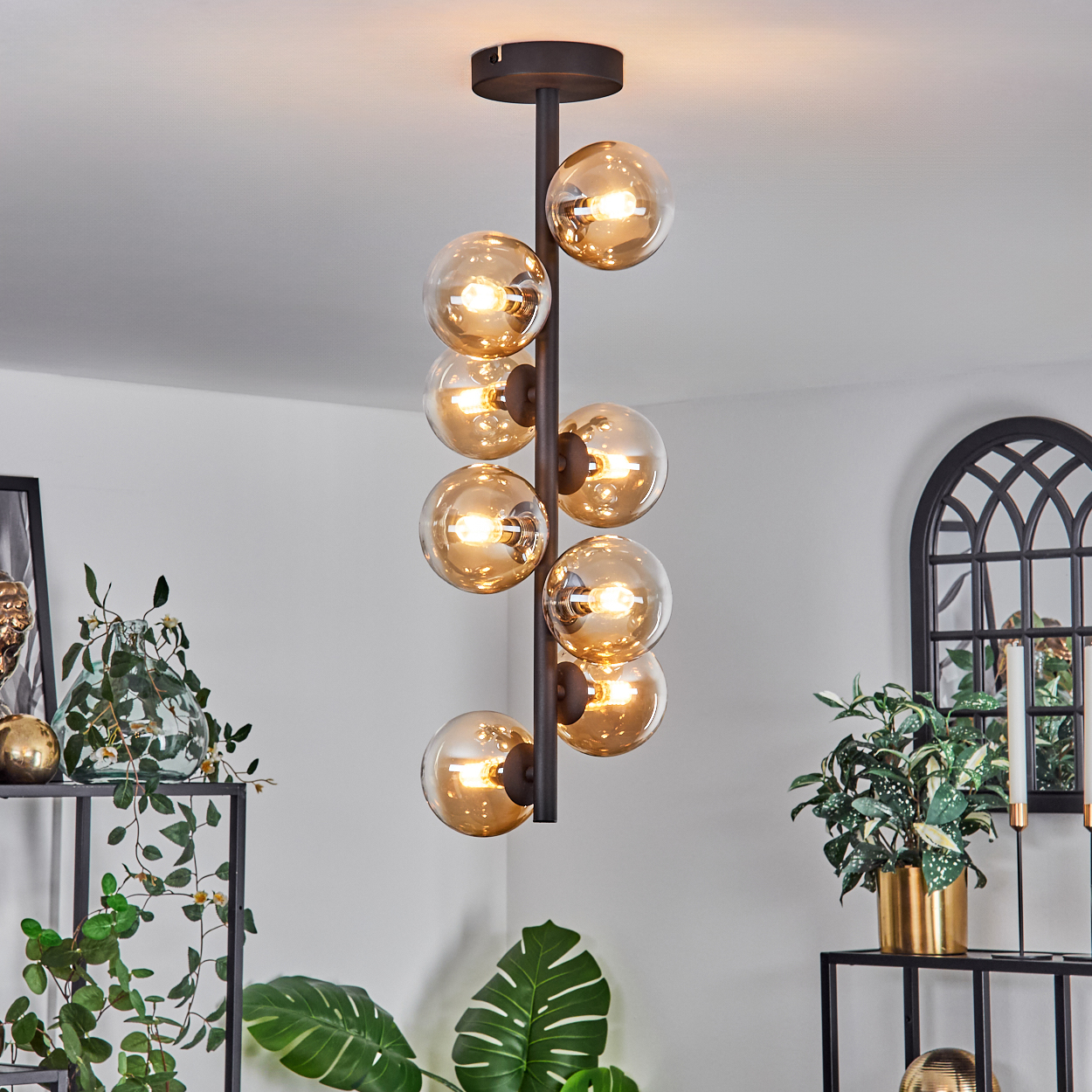 Ein moderner Kronleuchter mit mehreren bernsteinfarbenen Glaskugeln. Die Lampe hängt von der Decke.