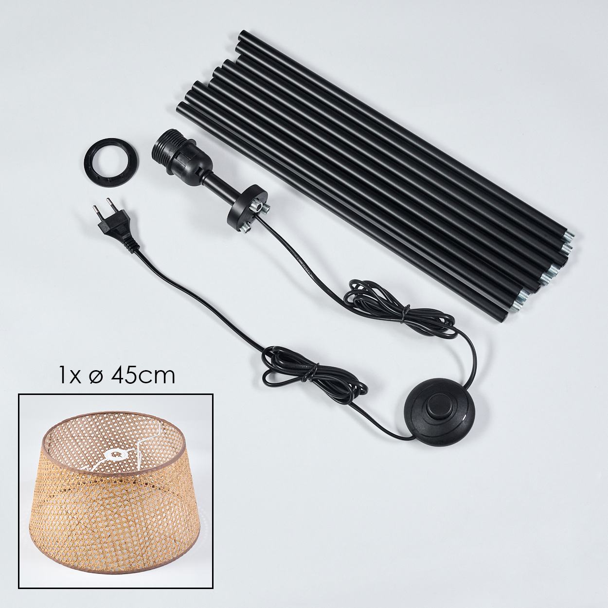 Komponenten einer Stehlampe: schwarze Stangen, Verkabelung, Schalter und ein Lampenschirm aus Rattan.