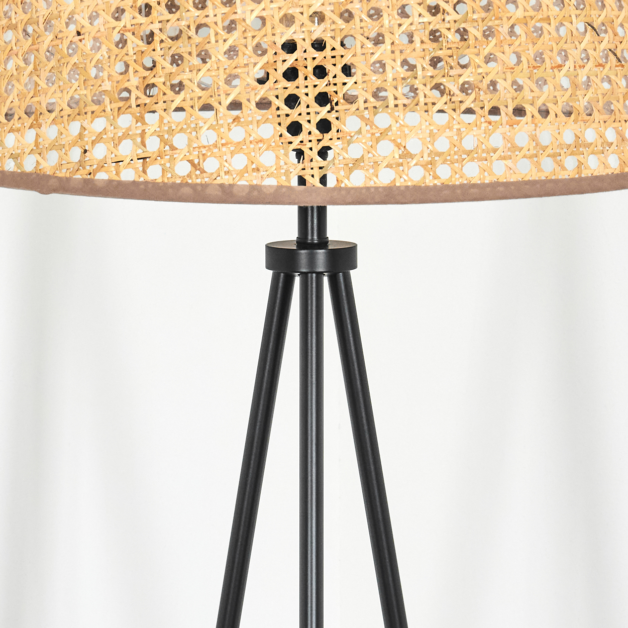 Nahaufnahme eines Lampenschirms mit beigem Rattan-Gewebe und einem schwarzen Metall-Dreibein-Sockel.