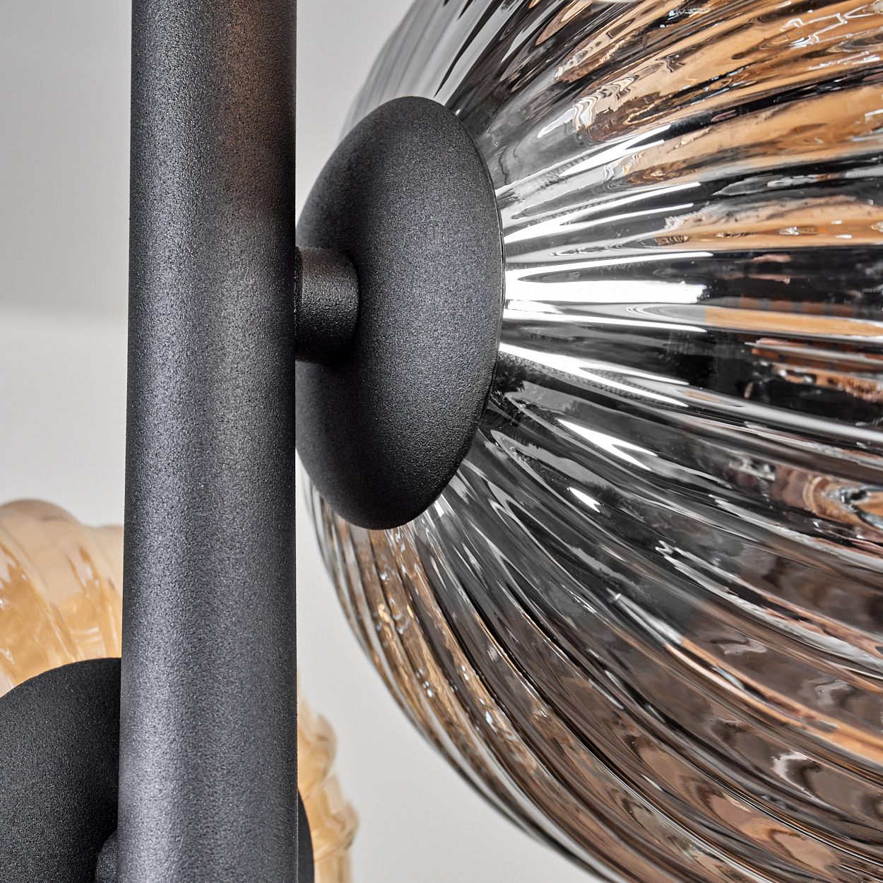 Nahaufnahme einer schwarzen Metallhalterung, die zwei Glaskugeln verbindet.