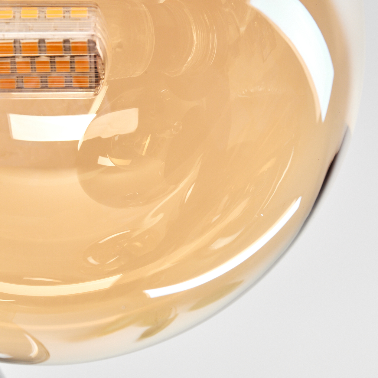 Nahaufnahme einer beleuchteten bernsteinfarbenen Glaskugel, die die Lichtquelle im Inneren und die Glasstruktur zeigt.