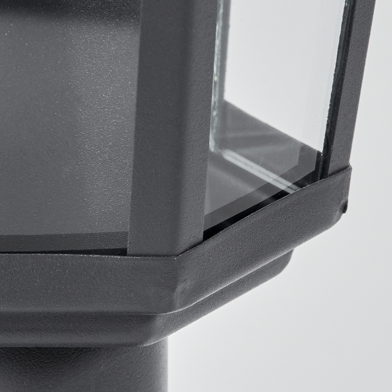 Nahaufnahme eines schwarzen, geometrischen Lampenmastkopfes mit Glasscheiben.