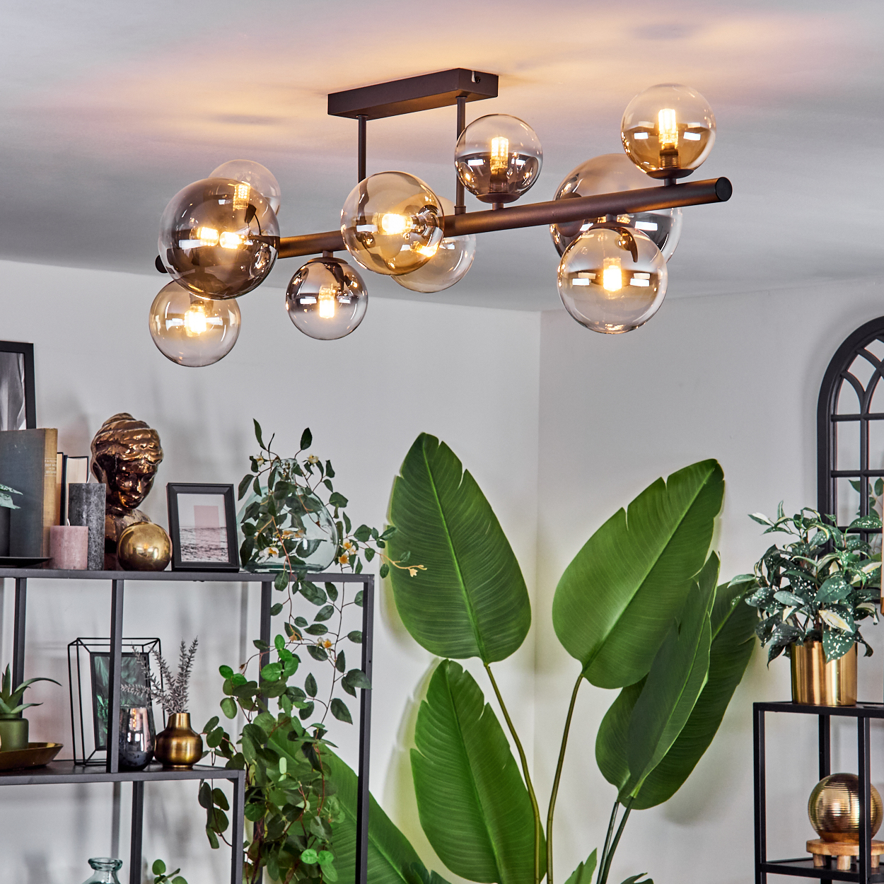 Deckenlampe mit mehreren bernsteinfarbenen und silbernen Glaskugeln. Die Lampe ist an einer weißen Decke montiert.