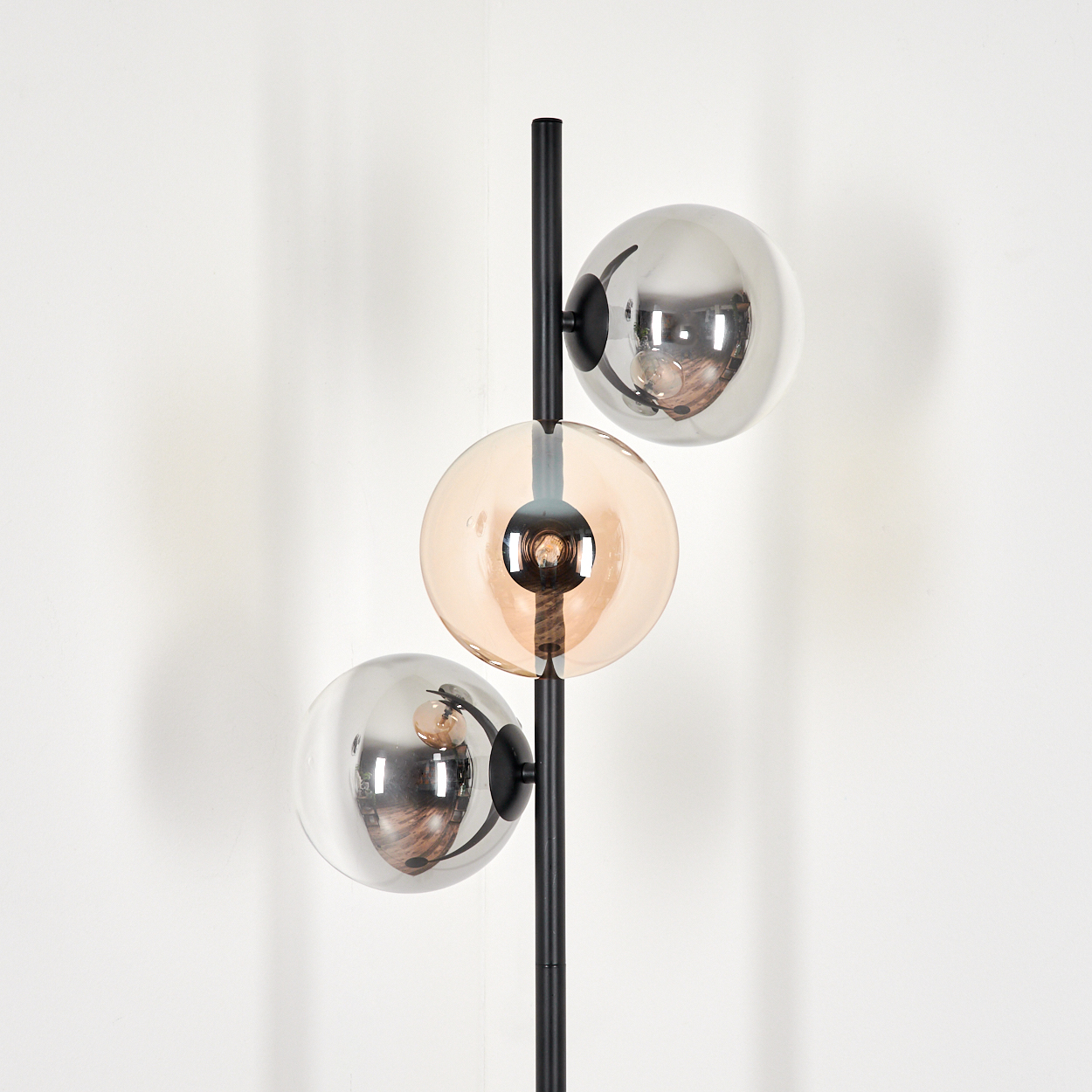 Nahaufnahme einer schwarzen Lampe mit drei Glaskugeln. Die Kugeln sind silber- und bernsteinfarben.
