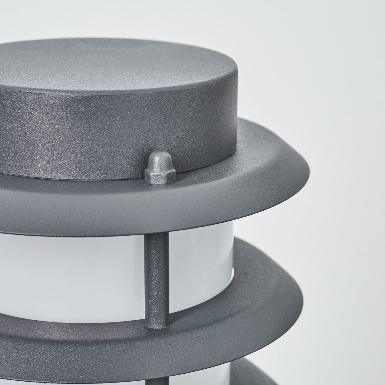 Nahaufnahme der grauen Außenlampe. Sie hat ein Spiraldesign mit weißem Licht im Inneren.