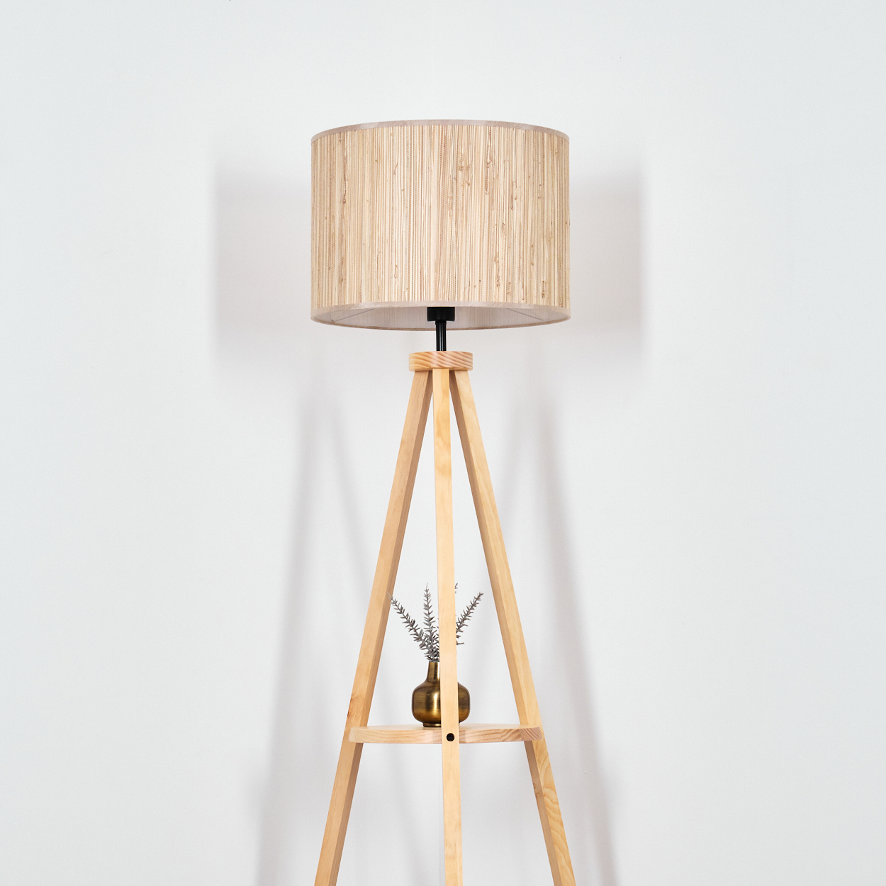 Stativ-Stehlampe aus Holz mit beigem zylindrischem Lampenschirm. Kleine Vase mit Pflanze.