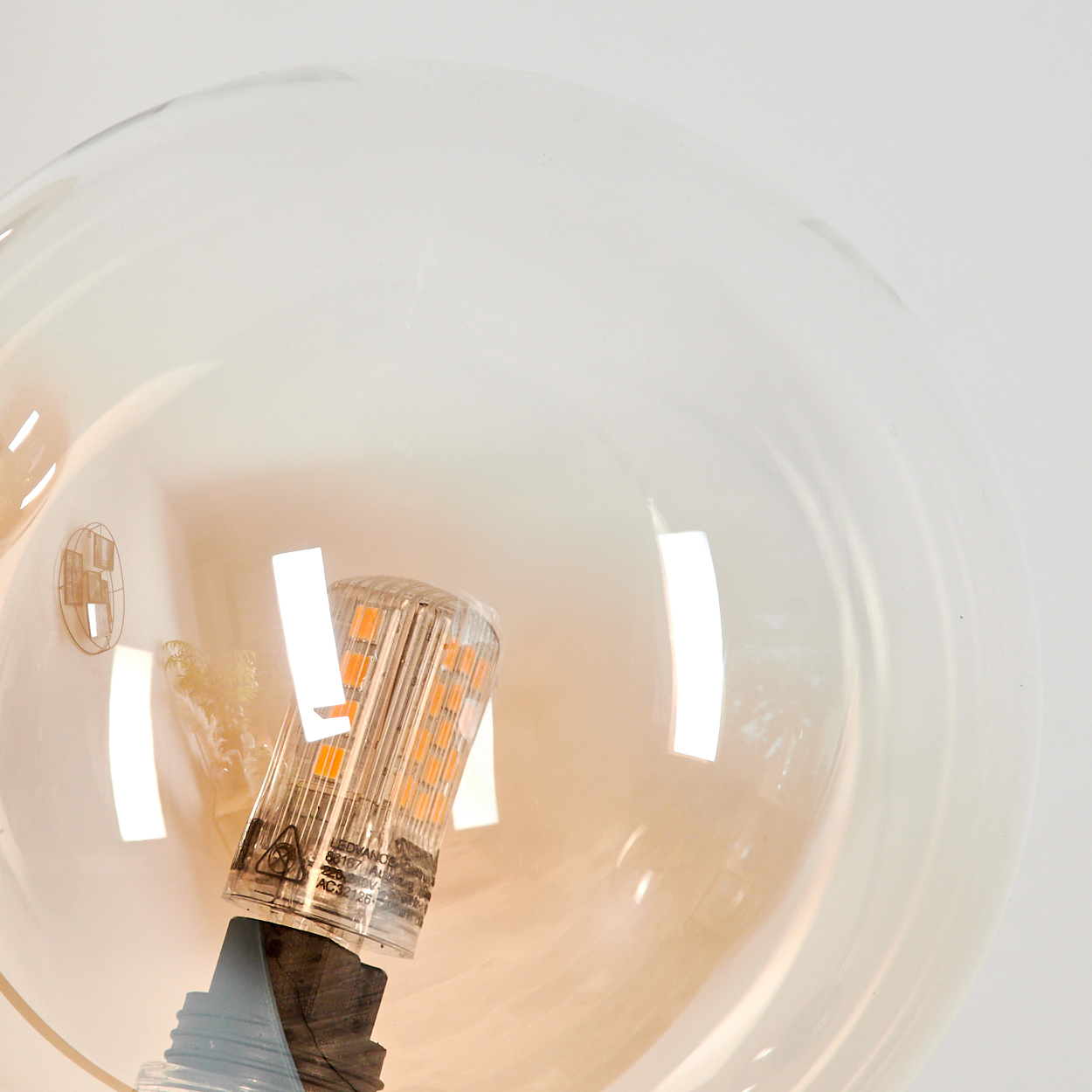 Nahaufnahme einer transparenten Glaskugel mit einer LED-Glühbirne im Inneren, die die Details der Glühbirne zeigt.