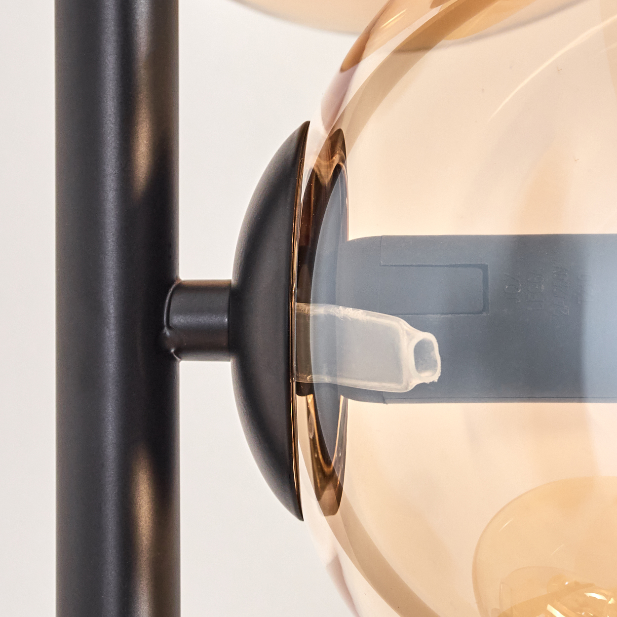 Nahaufnahme des Glühbirnenhalters einer Stehlampe mit bernsteinfarbenem Glaskolben.