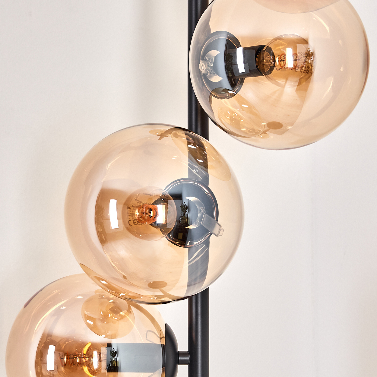 Nahaufnahme einer Stehlampe mit drei bernsteinfarbenen Glaskugeln, die die Wendelfäden der Glühbirnen zeigen.