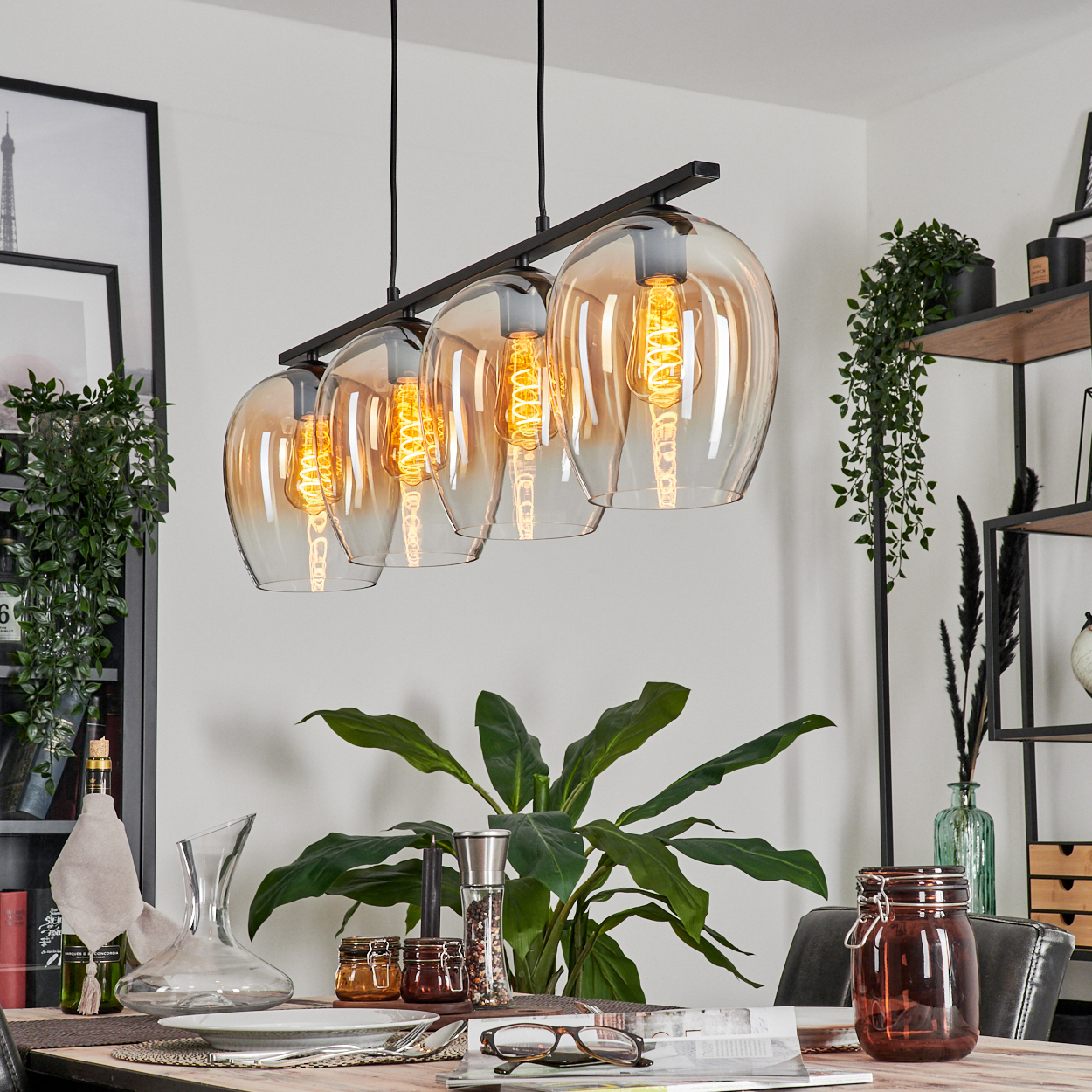 Ein Esszimmer mit einem vierflammigen Kronleuchter mit bernsteinfarbenen Glasschirmen.