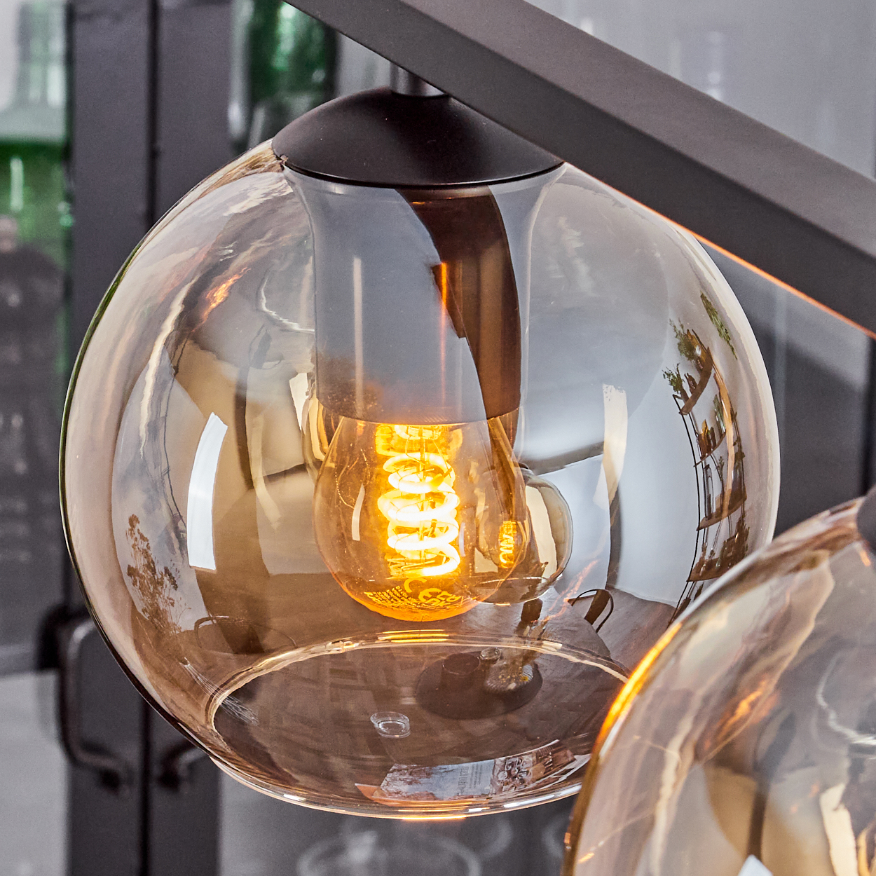 Nahaufnahme einer beleuchteten Edison-Glühbirne in einer bernsteinfarbenen Glas-Pendelleuchte.