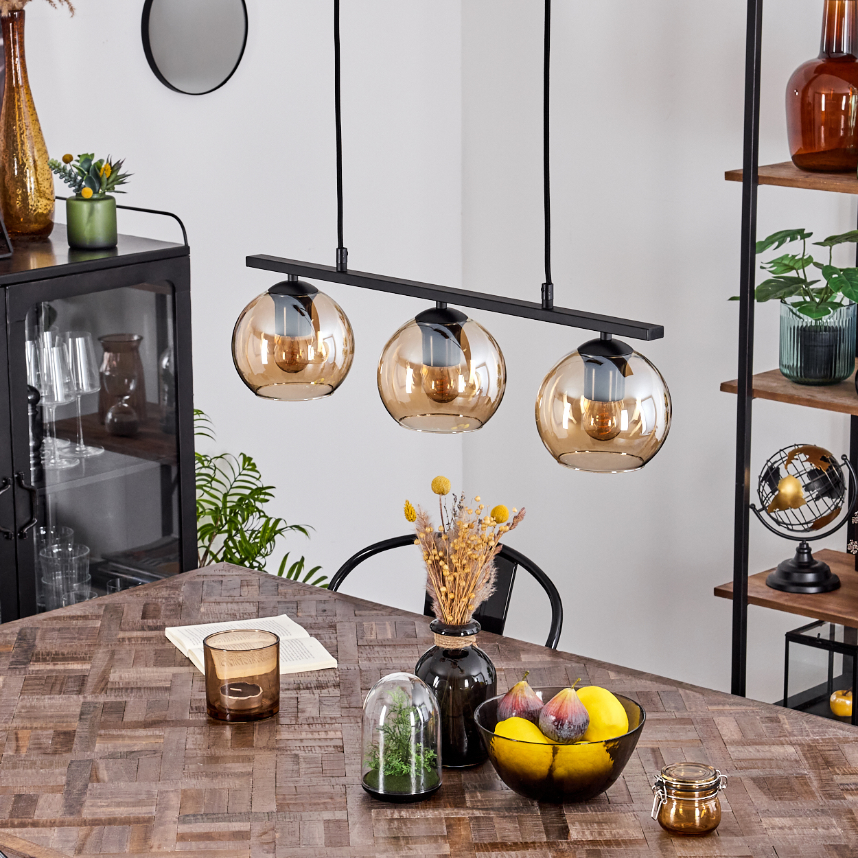 Esszimmer mit Holztisch, schwarzer Lampe mit Bernsteinkugeln und verschiedenen Dekorationen.
