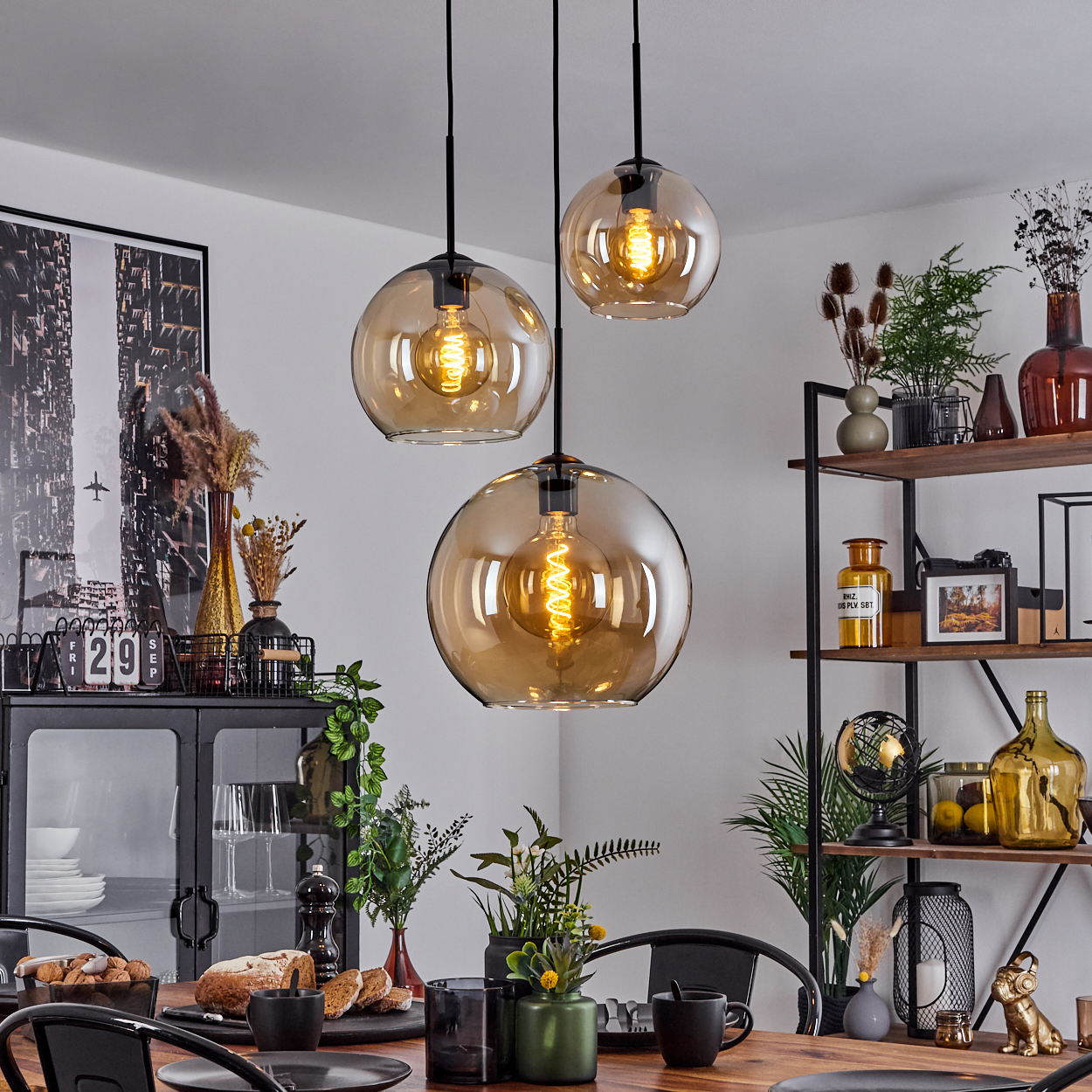 Esszimmer mit Hängelampen mit Bernsteinkugeln, einem Tisch und verschiedenen Dekorationsartikeln.