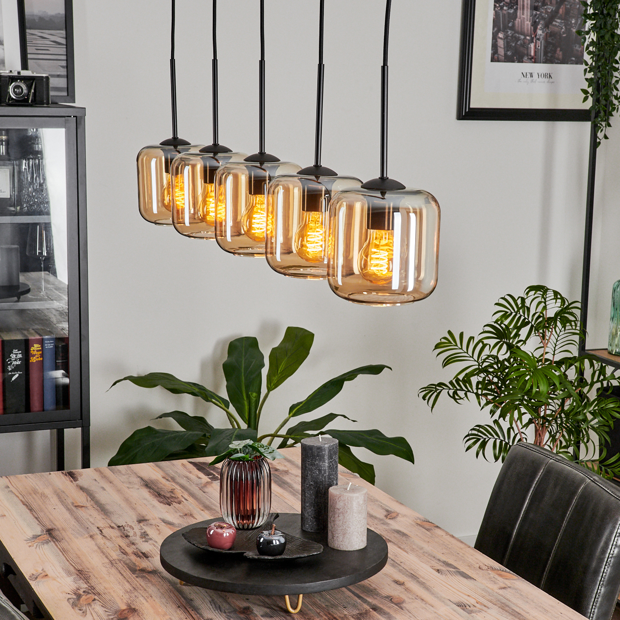 Esszimmer mit Holztisch und einer Leuchte mit sechs bernsteinfarbenen Glasschirmen.