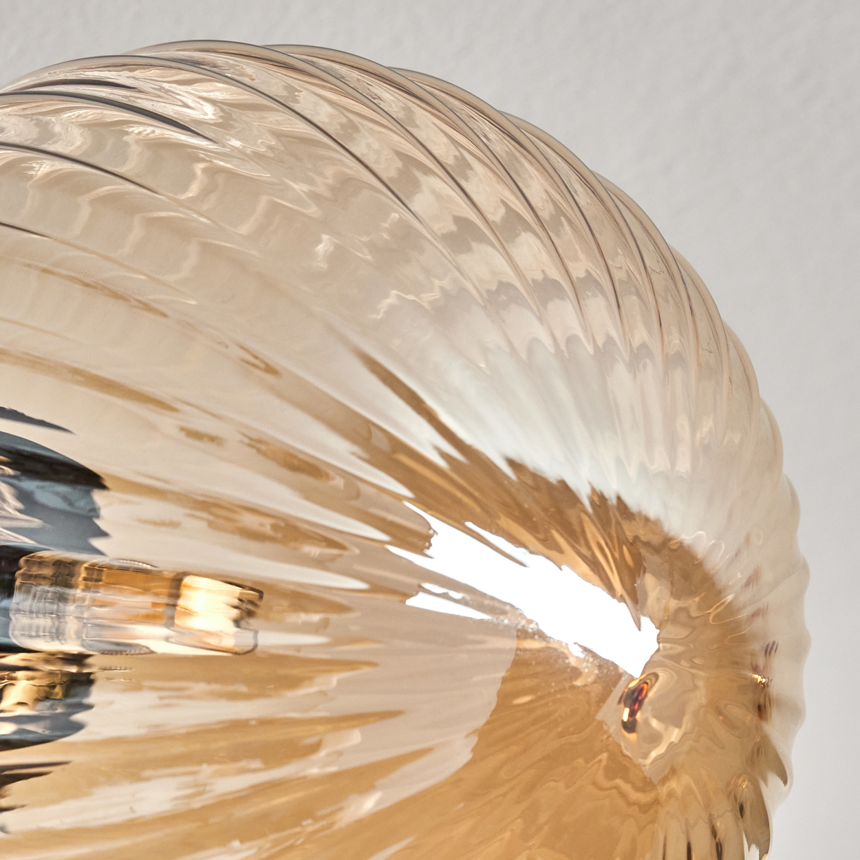 Nahaufnahme einer gerippten bernsteinfarbenen Glaskugel, beleuchtet von Innenlicht.
