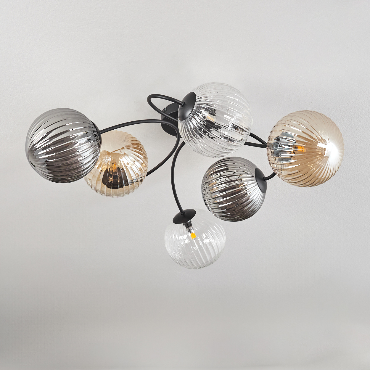 Eine Deckenlampe mit sechs Lampenschirmen. Einige sind silbern, andere bernsteinfarben. Die Halterung ist schwarz.