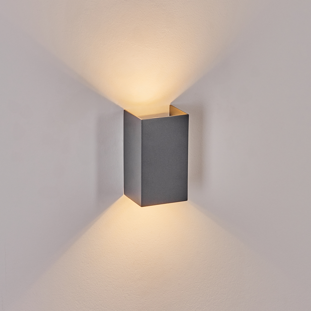 Eine moderne, dunkelgraue Wandleuchte, die ein warmes Licht ausstrahlt.