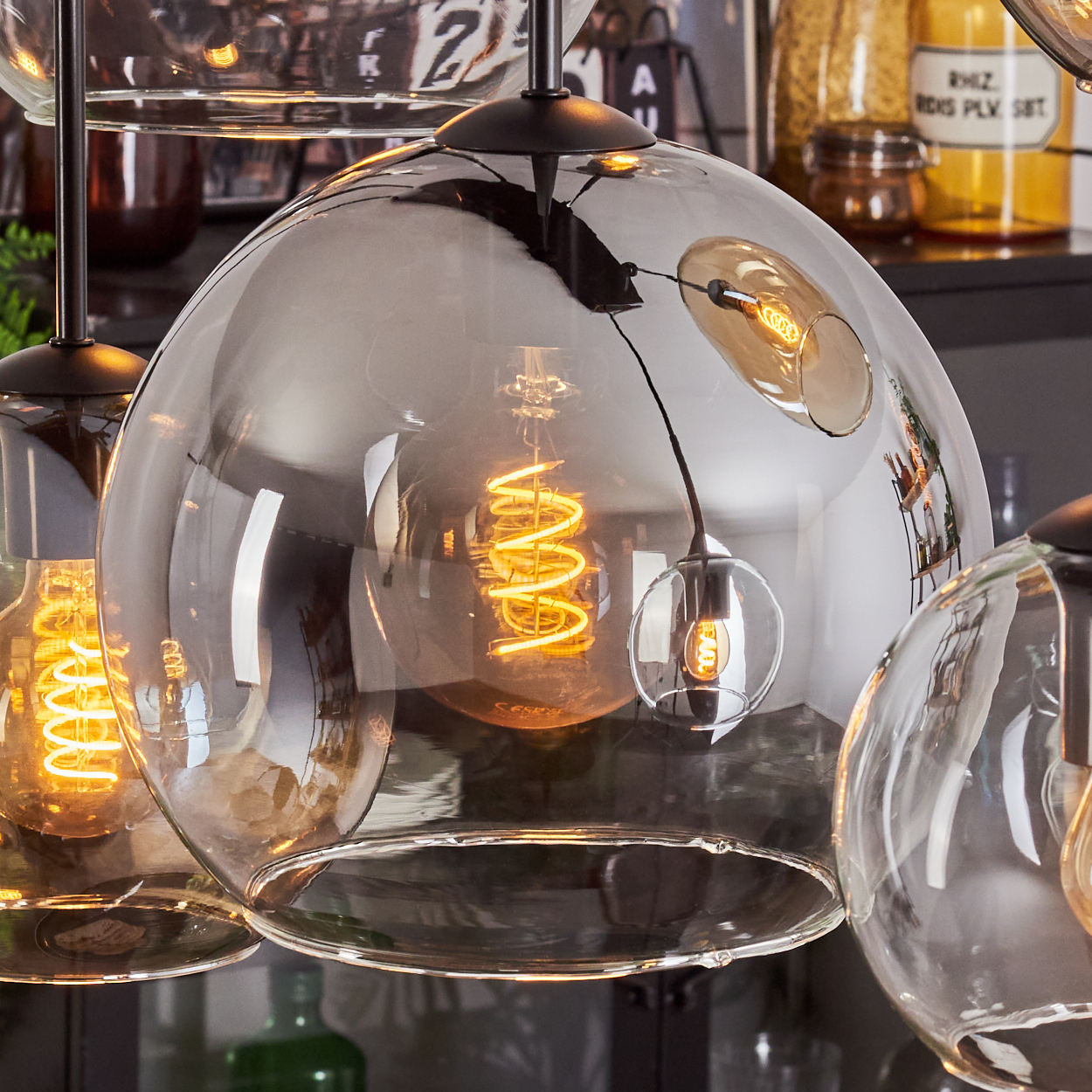 Nahaufnahme mehrerer Glaslampen mit Wendelglühbirnen. Die Lampen haben ein schwarzes Metall-Finish.