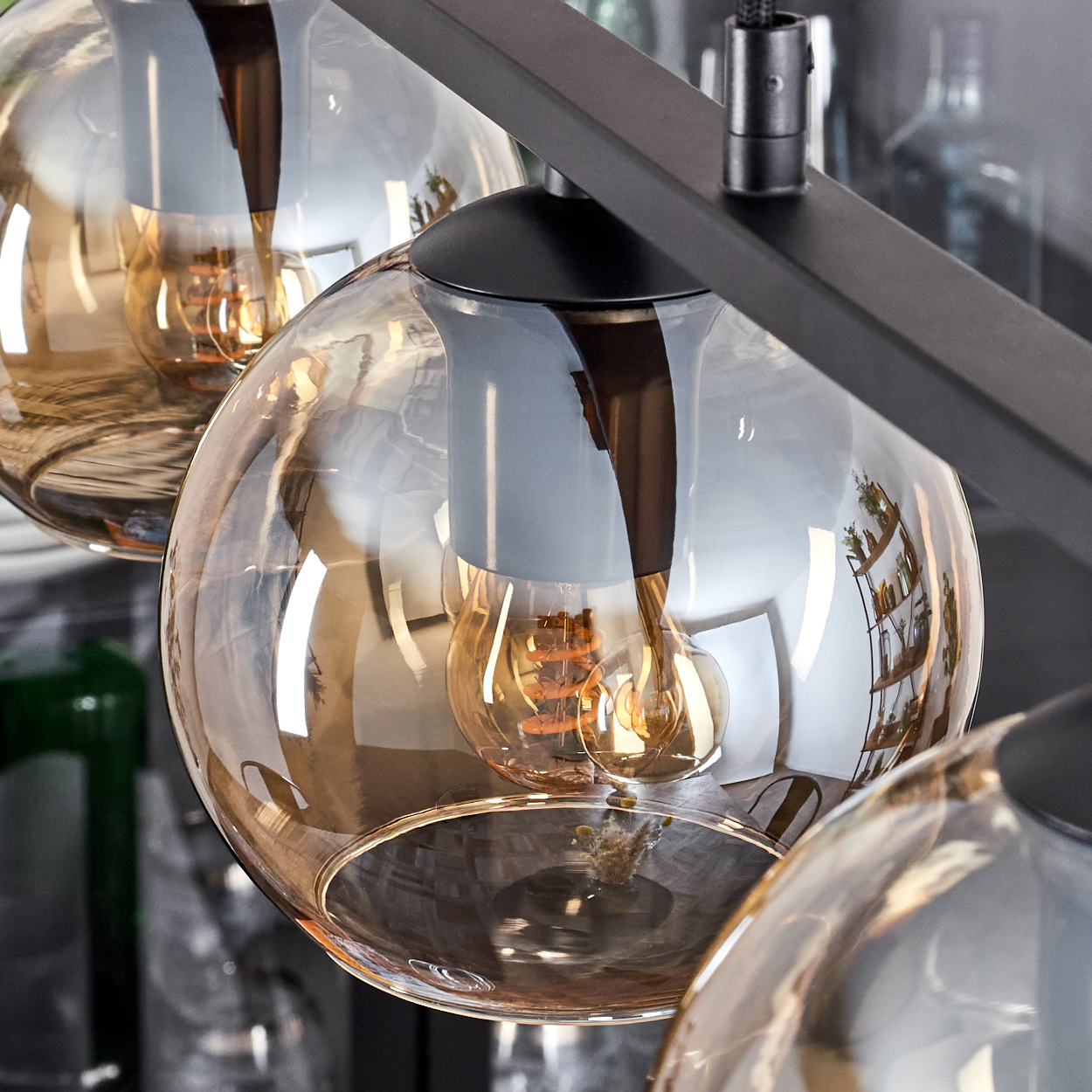 Nahaufnahme einer schwarzen Lampe mit Glasschirmen, die jeweils eine warme Glühbirne enthalten.